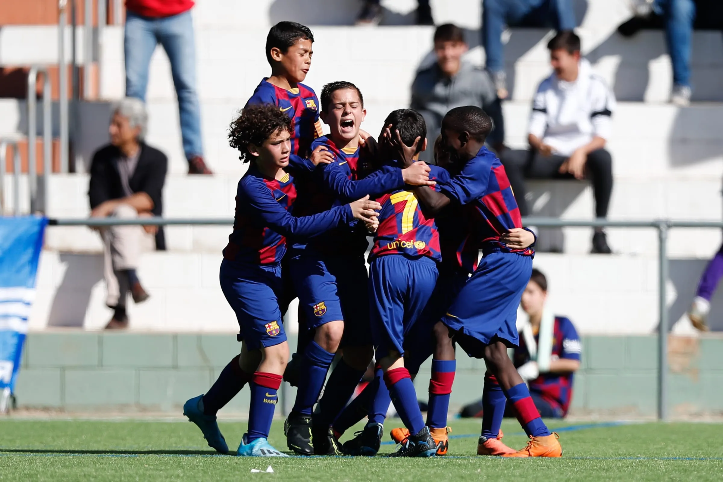 Jugadores alevines del FC Barcelona celebrando juntos en el campo