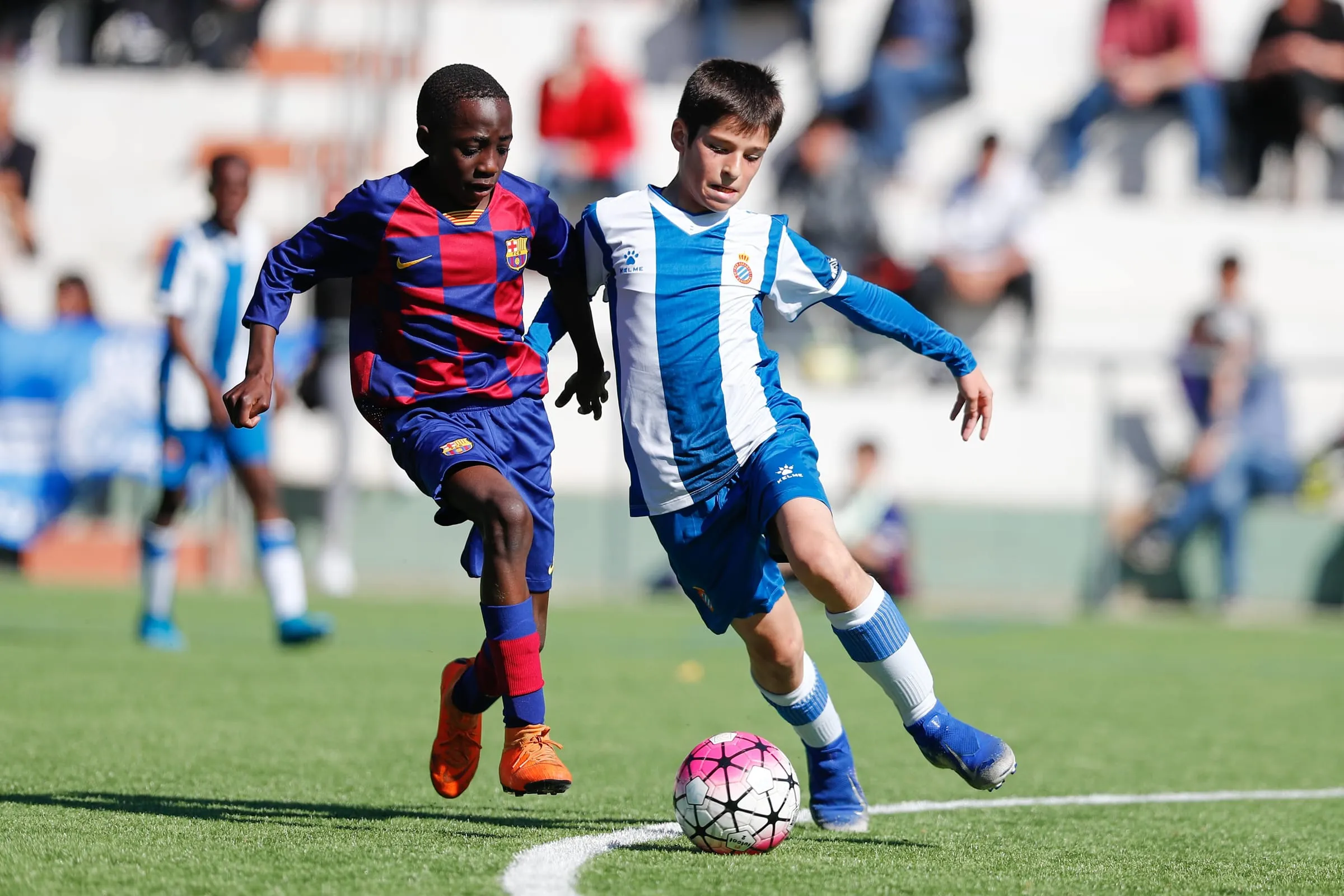 Un jugador del FC Barcelona y otro del RCD Espanyol persiguen el balón