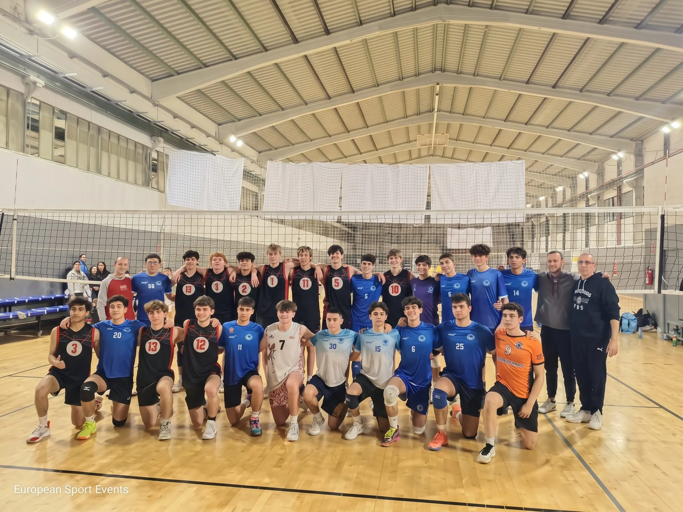 Dos equipos de voleibol y sus entrenadores posan junto a la red tras un partido amistoso