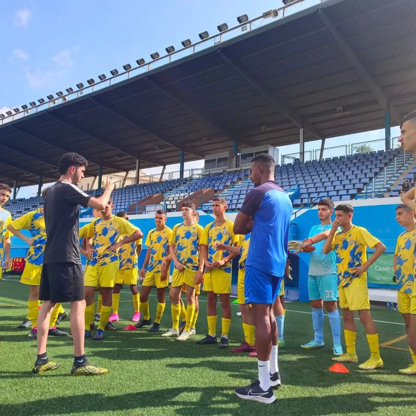 Un entrenador da instrucciones a un equipo juvenil en un campo de fútbol